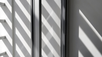 Selective focus at glass window sill, side view and diagonal pattern of sunlight and shadow shining through from outside of building in black and white style