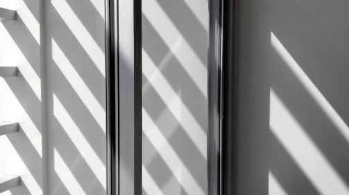 Selective focus at glass window sill, side view and diagonal pattern of sunlight and shadow shining through from outside of building in black and white style